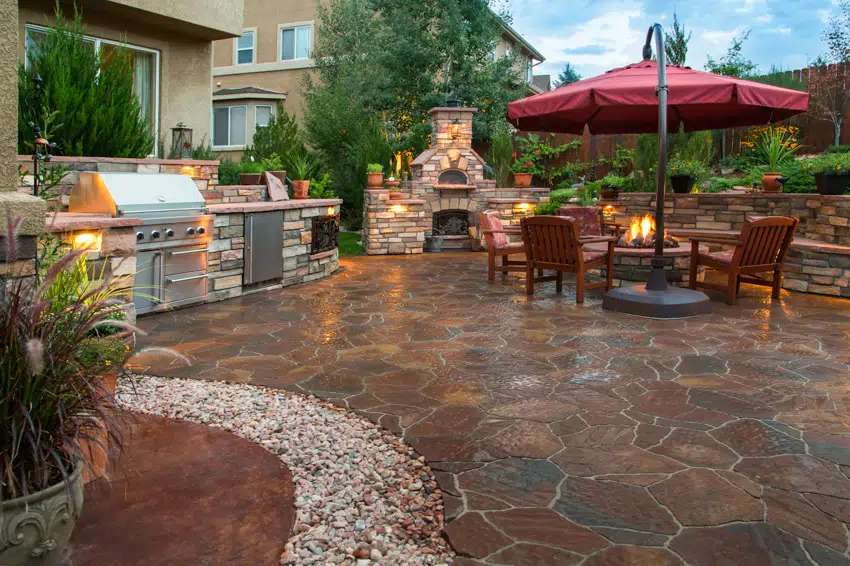Outdoor kitchen with stone fire pit dining area and grill