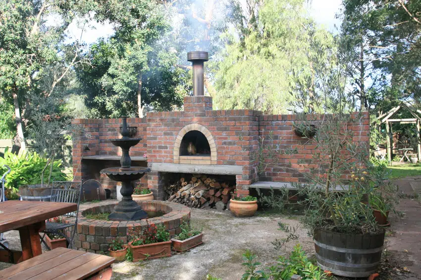 Outdoor pizza oven with old fountain and trees