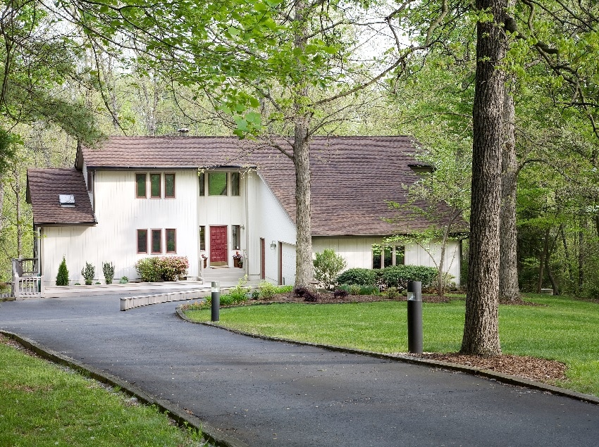 Residential home with asphalt driveway surrounded with grass and trees