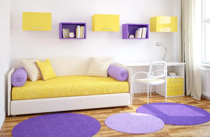 Room with yellow and beige sofa, purple mats, cabinets, white armchair and table