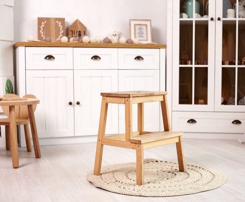 Small cute heart shaped chair and table little wooden ladder on a round rug with pads in the middle of the room