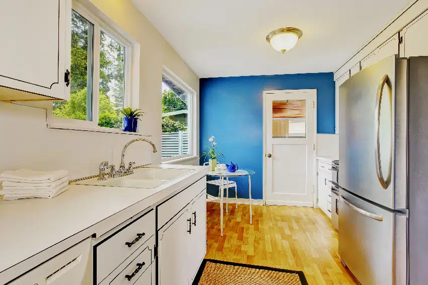 small kitchen room interior with white cabinets navy blue walls and glass dining table