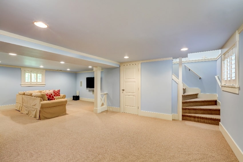 Spacious basement in pastel blue tones and beige carpet floor