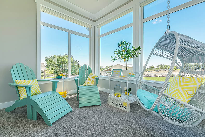 Sunroom with pops of color teal furniture cushions swinging chair