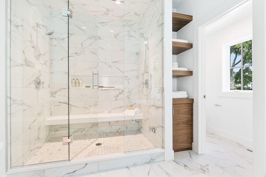 White bathroom with shower bench glass door and wood shelves