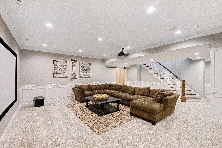 white wall with light carpet and big brown sectional sofa in basement room