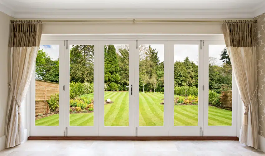 Wide folding patio door with curtains leading to backyard