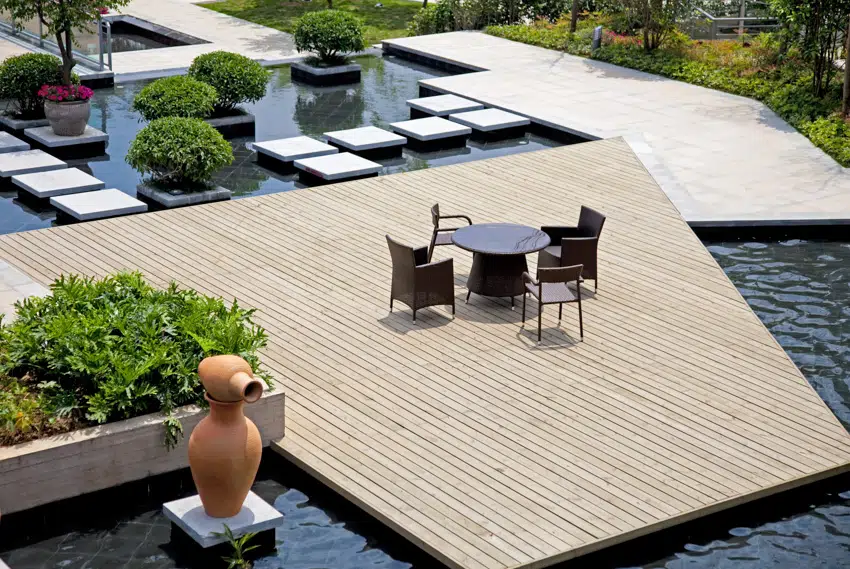 Wooden deck in the middle of pool with table and chairs on it