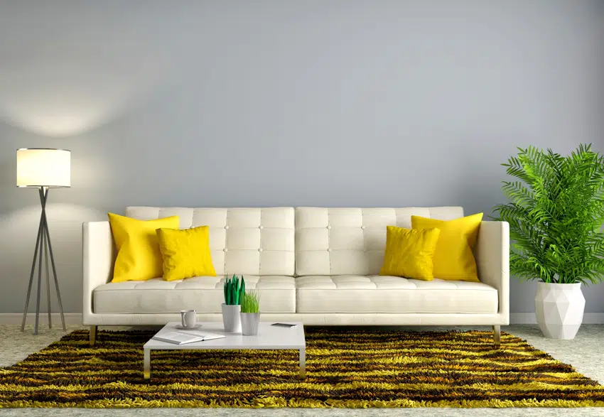 living room interior with white sofa plant floor lamp coffee table and a golden carpet