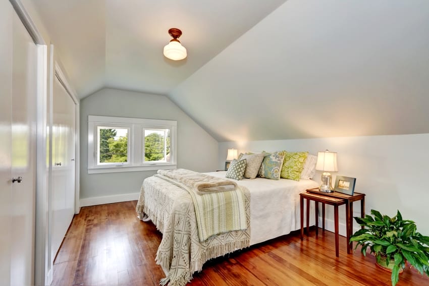 attic bedroom interior with vaulted ceiling and honey oak wood floor a nice bed cover and colorful pillows