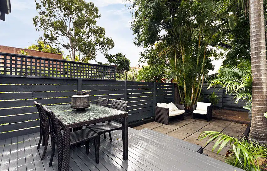 Backyard deck with dark brown painted fence with lattice top