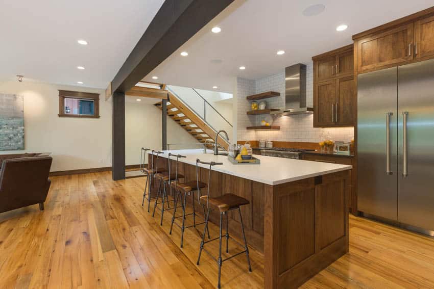 Basement kitchen with hickory wood floor center island stools refrigerator and ceiling lights