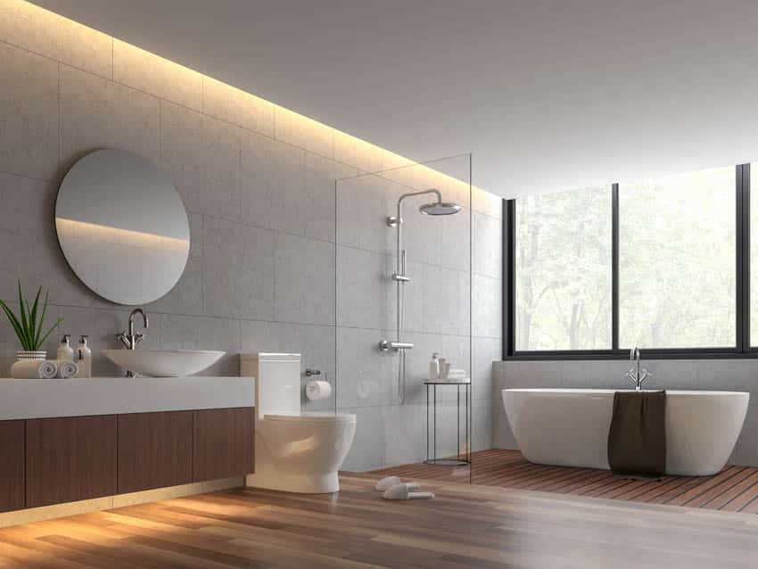Bathroom with circular mirror bathtub shower area toilet sink and wood flooring