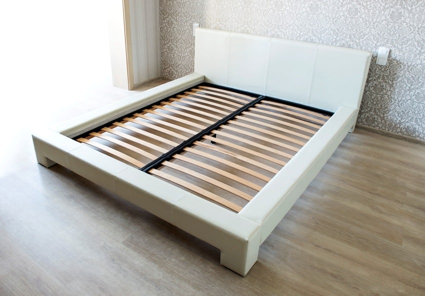 bed in bedroom with wooden slats without mattress