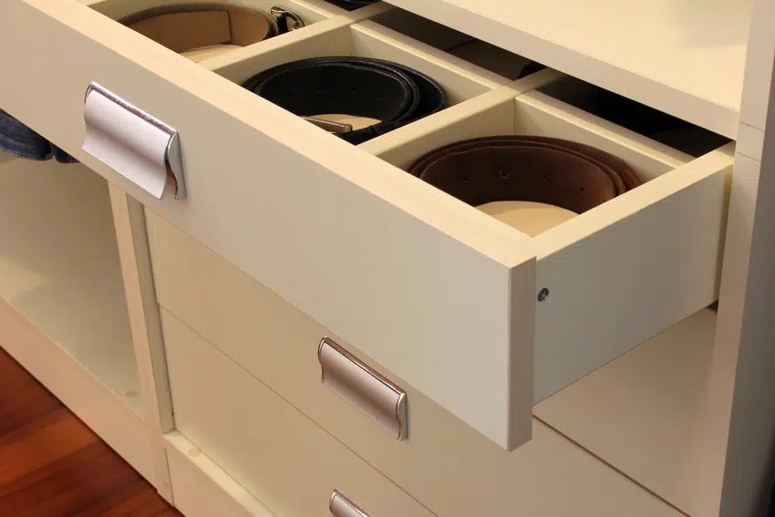Belts coiled inside white drawer 