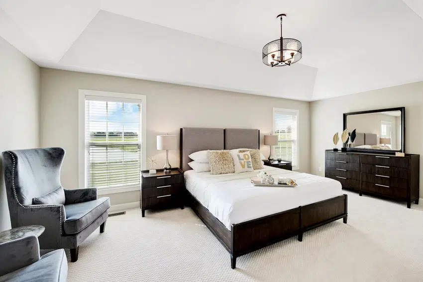 Big bedroom with dark colored furniture and hanging ceiling light