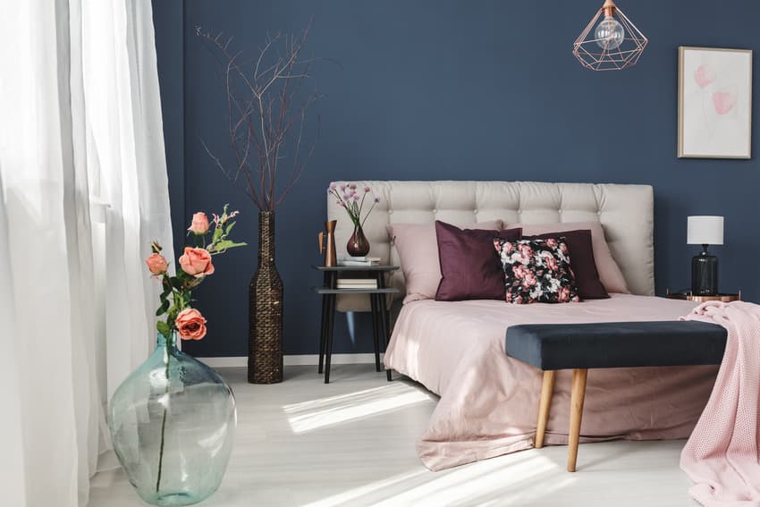 Contemporary bedroom with navy blue walls comfy bed and various decorative pieces