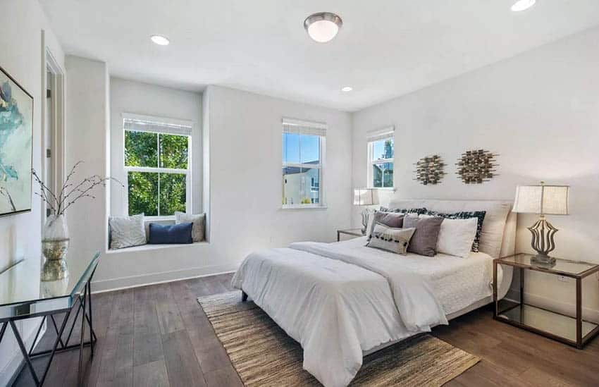 Contemporary master bedroom with hardwood look laminate flooring and window seat