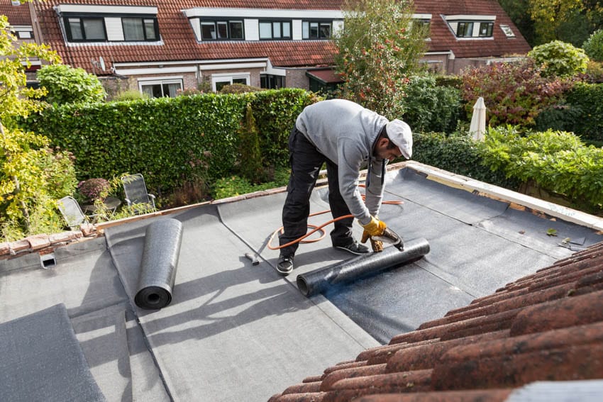 Contractor installing rolled roof underlayment