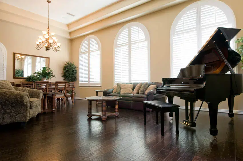 Dining area combined with living room with dark wood floors and pastel yellow paint grand piano