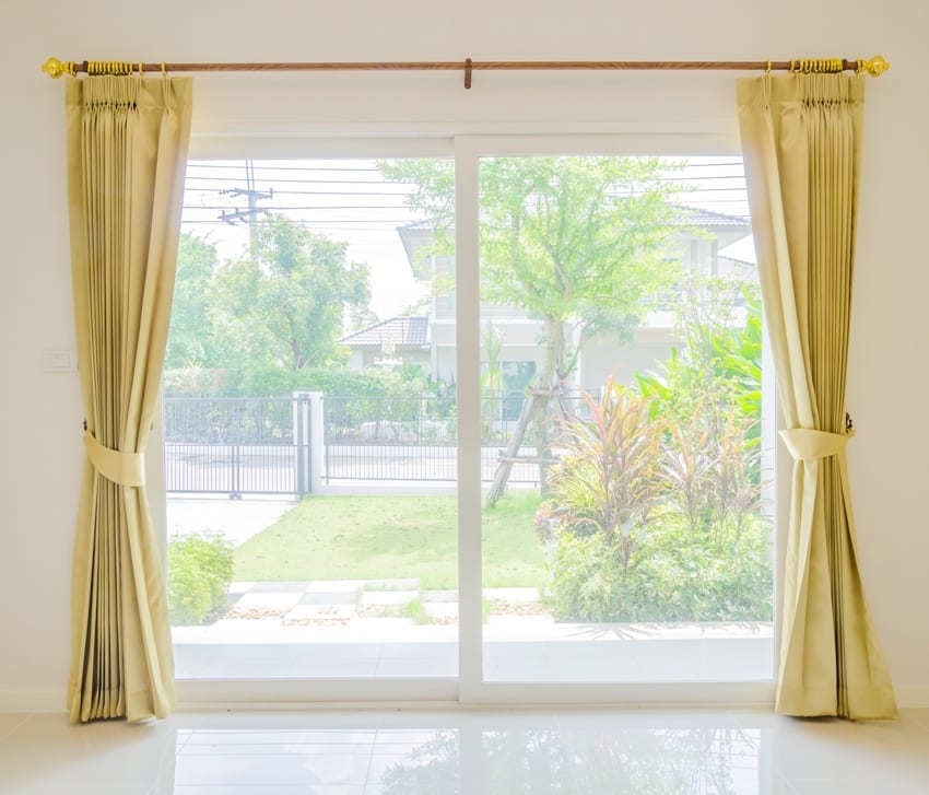 empty room with glass doors sage green curtains and a garden view