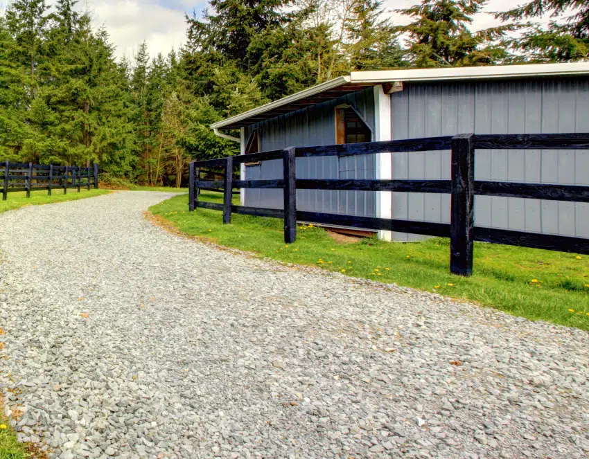 Farm with gravel driveway fence and shed with green grass
