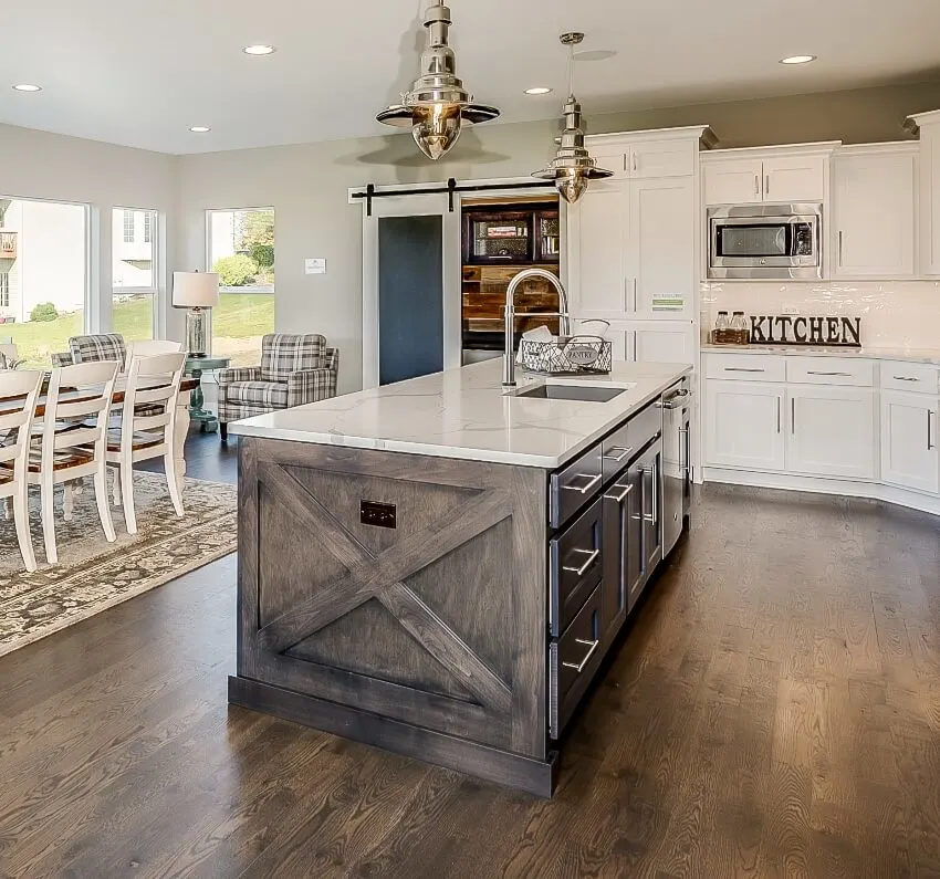 Farmhouse style kitchen with rustic style island slightly vaulted ceiling with many windows letting in natural light