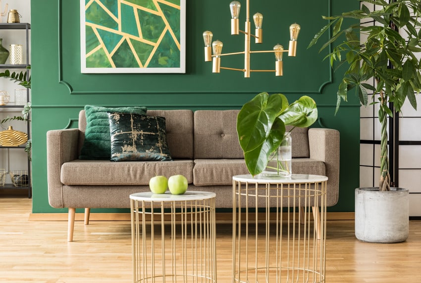 Green and gold living room interior with comfortable brown sofa and coffee tables