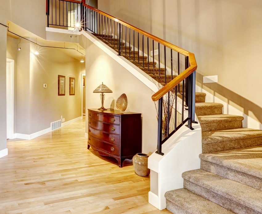 hallway with high ceiling a staircase wooden floors and drawer