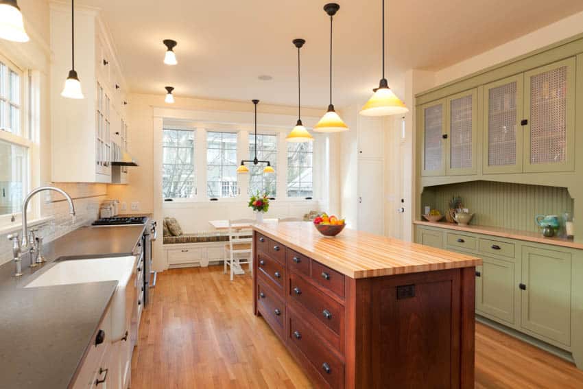 Kitchen with booth near window, island, wood floor two tone cabinets and pendant lights 