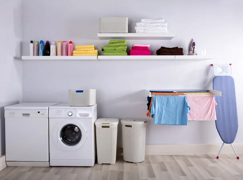 laundry room interior with washing machine ironing body baskets and drying clothes