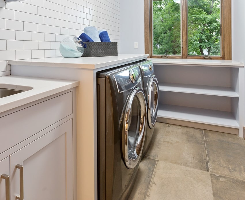 laundry with front loading washer and matching dryer a subway tile wall and countertop