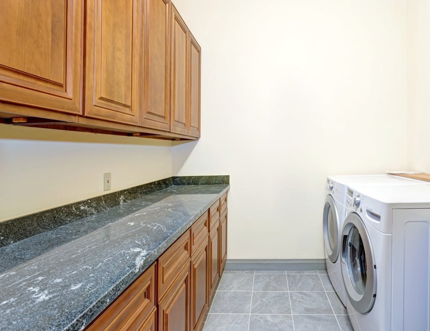 laundry room with marble countertop wooden cabinets and white laundry appliances