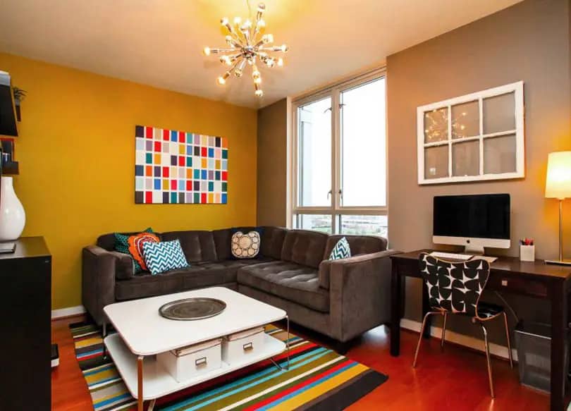 Living space with gold accent wall brown wall paint and sputnik chandelier