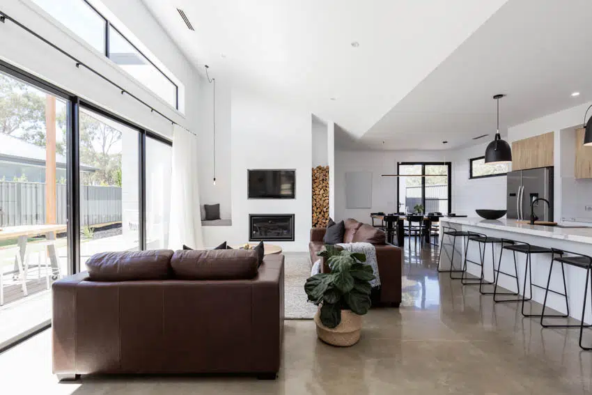 Living room with large windows polished concrete floors bar area and dining space