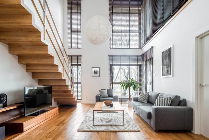 Living room with wood flooring sofa chair television and large windows