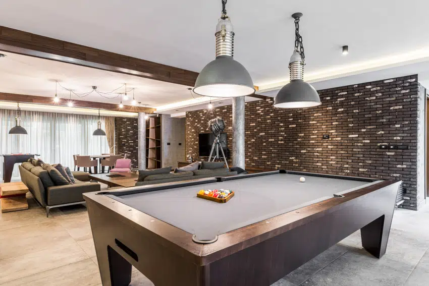 Man cave with billiards table sofa chairs and pendant lighting