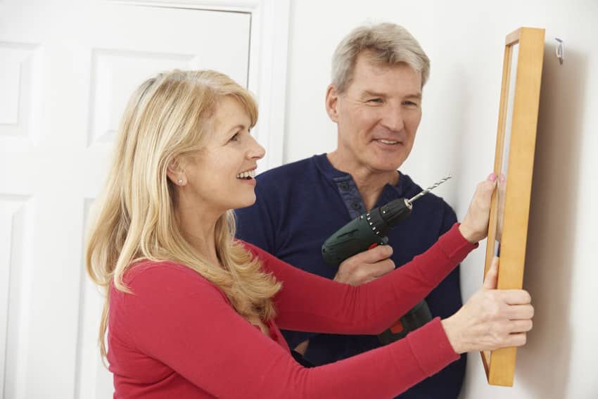 Man drilling wall to hang frame