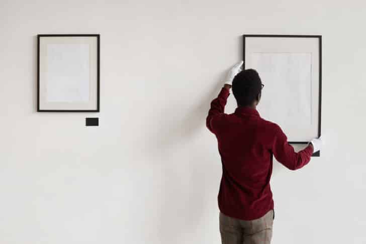 How To Hang Up Heavy Frames Without Nails   Man Hanging Frame On A Wall Is 728x486 