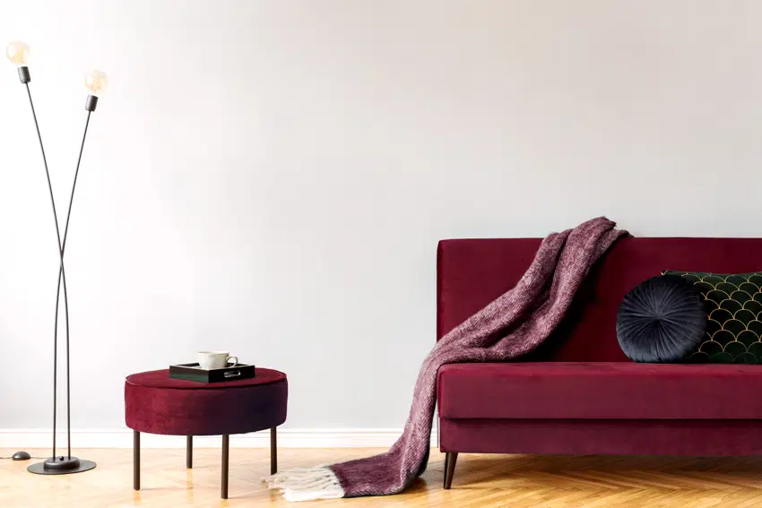 minimalistic home interior with gray wall burgundy velvet design sofa and pouf black lamp