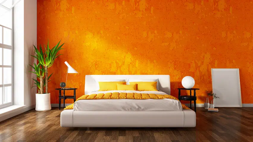 Modern bedroom interior with orange walls pillows and wooden flooring