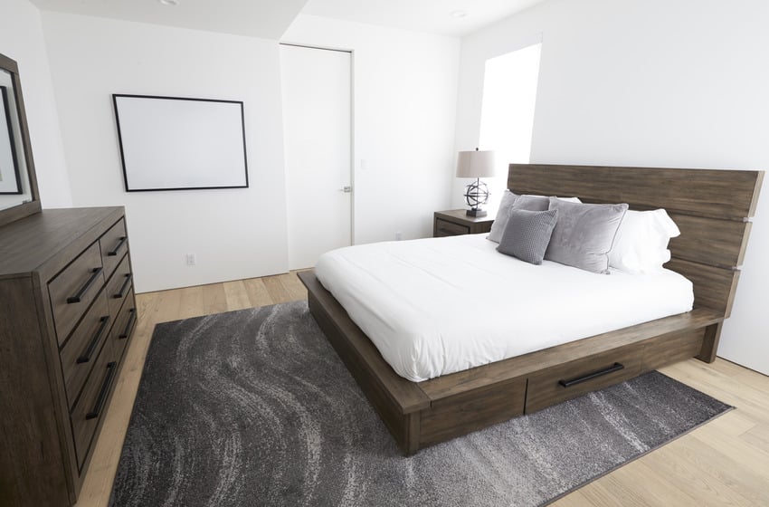 Modern bedroom interior with wooden bedframe furniture and stylish rug