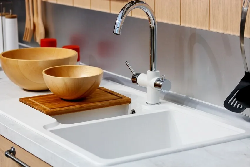 Modern kitchen interior with wooden bowl on chopping board faucet and sink on foreground