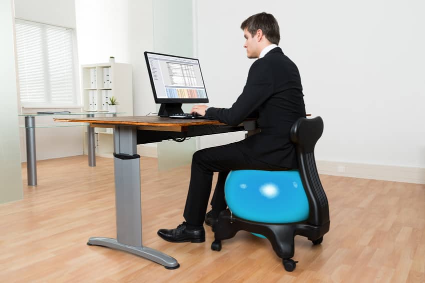 Man in office sitting on exercise ball