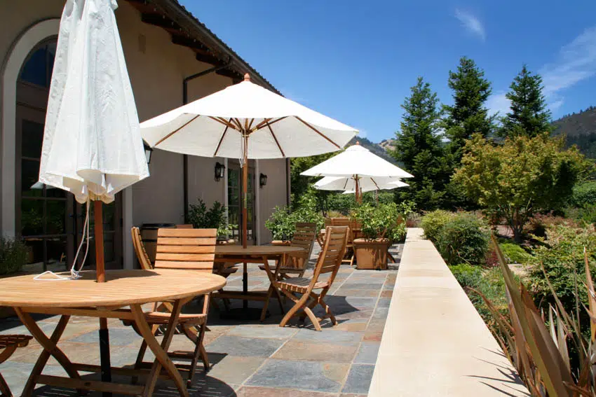 Outdoor patio with wooden chairs and tables slate tiles