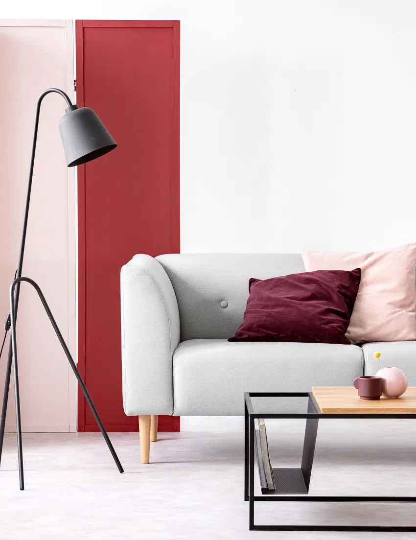 pastel pink and burgundy pillows on grey sofa in elegant scandinavian living room with burgundy pink and white wall