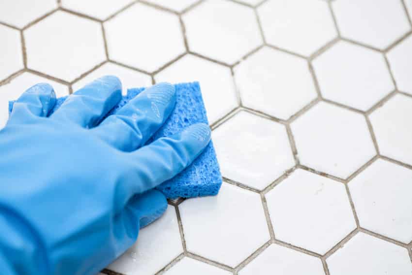 Person with gloves cleaning tile and grout