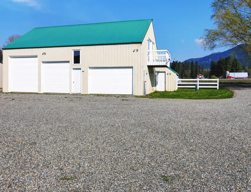 Separate garage building with three garage doors and gravel driveway around
