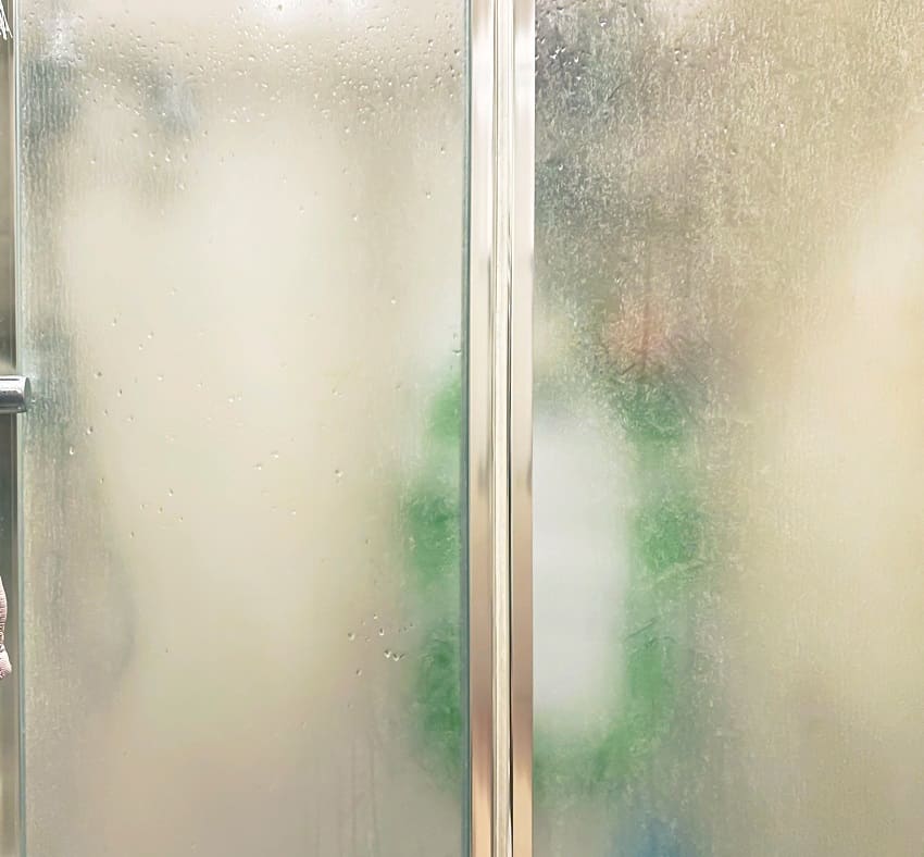 Shower enclosure with frosted glass doors and aluminum structure inside a bathroom
