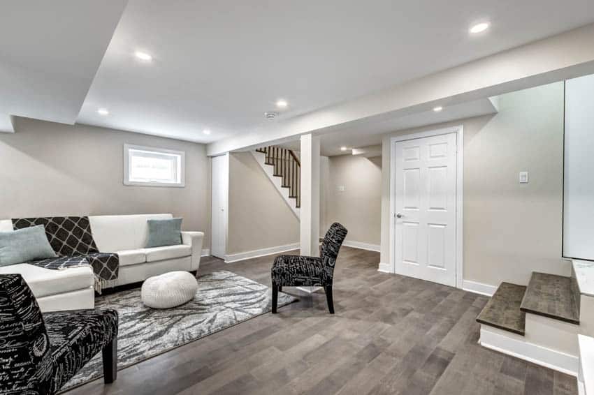 Spacious basement with wooden floor sofa chairs and ceiling lights